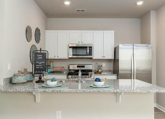 Homes For Rent In Myrtle Beach SC - The Palmer At Carolina Forest - Kitchen with Granite Countertops, Stainless Steel Appliances, and Crisp White Cabinets with Round Nickel Hardware
