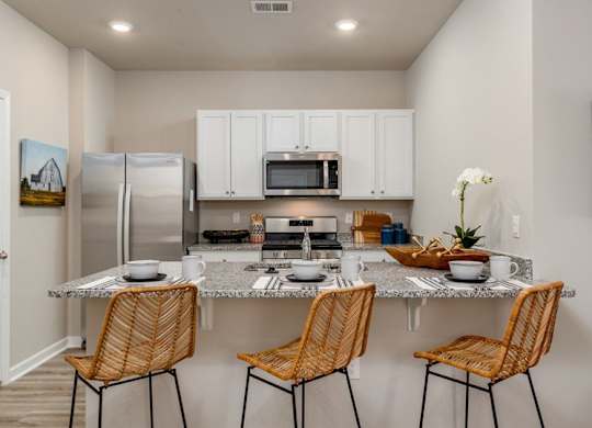 a kitchen with a counter top and three chairs