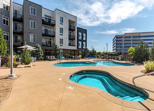 our apartments have a pool and hot tub with an apartment building in the background