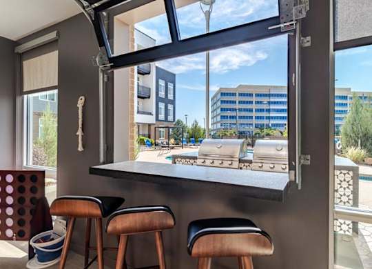a bar with three stools in front of a large window
