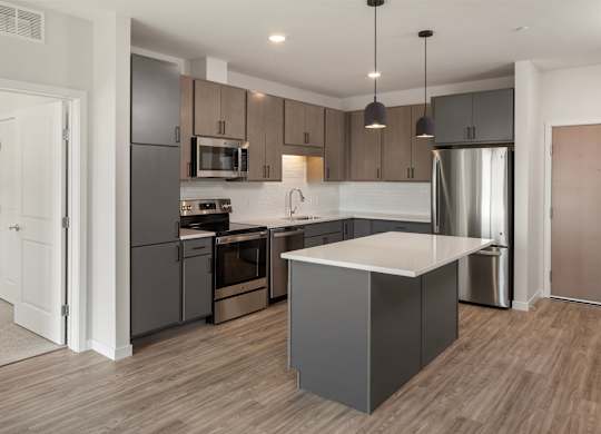 A modern kitchen with a large island and stainless steel appliances.