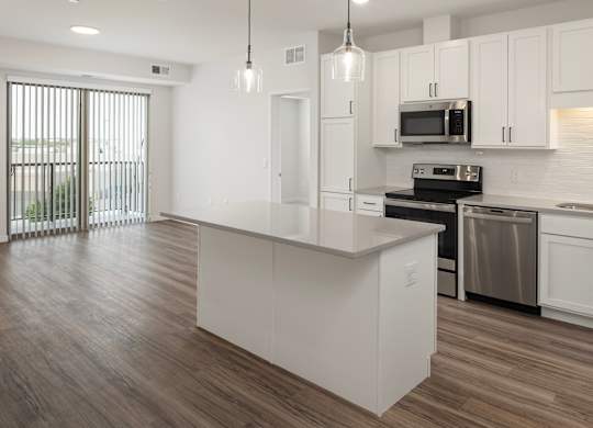 A modern kitchen with white cabinets and a wooden floor.