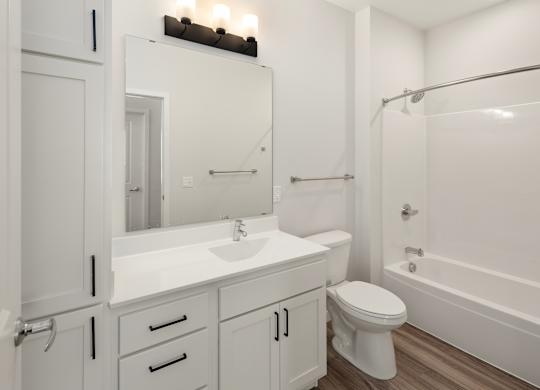 A white bathroom with a toilet, sink, and bathtub.