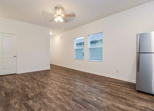 A room with a ceiling fan and a refrigerator.