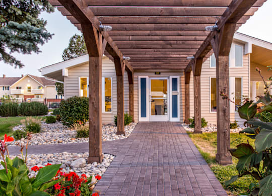 Covered pergola walkway leading to leasing office at Aurora Meadows apartments.