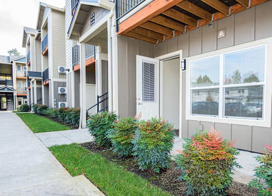an exterior view of an apartment building with a sidewalk