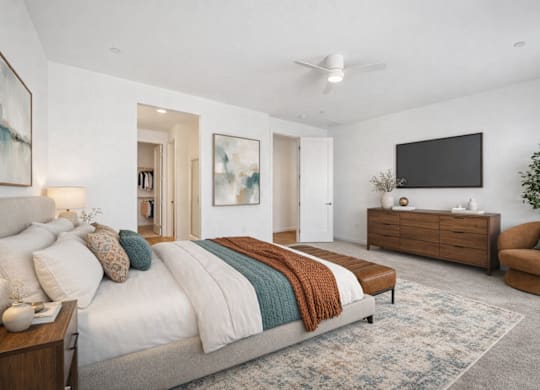 A bedroom with a large bed, a chair, and a TV mounted on the wall.
