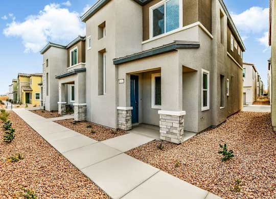 a street view of a house with a sidewalk and landscaping