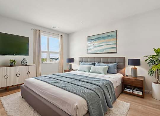 A bedroom with a large bed and a painting on the wall.