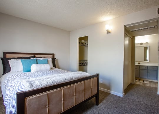 1-Bedroom Apartments in Tucson, AZ - Peaks at Redington - Bedroom with Carpeted Floor, Full-Size Bed, Spacious Closet with Clothes Hangers, and Attached Bathroom.