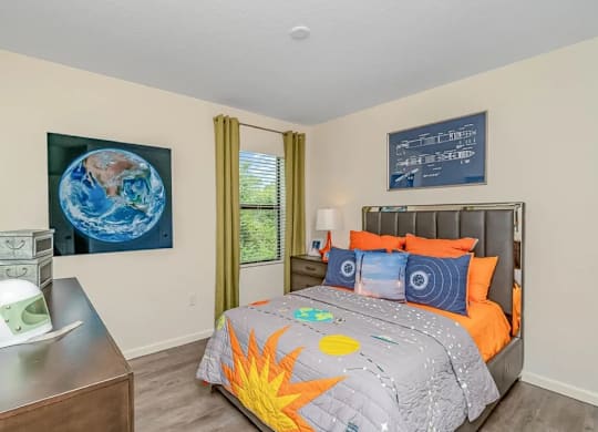 A bedroom with a bed, a dresser, and a painting of the Earth on the wall.