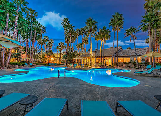 A pool surrounded by palm trees at dusk.