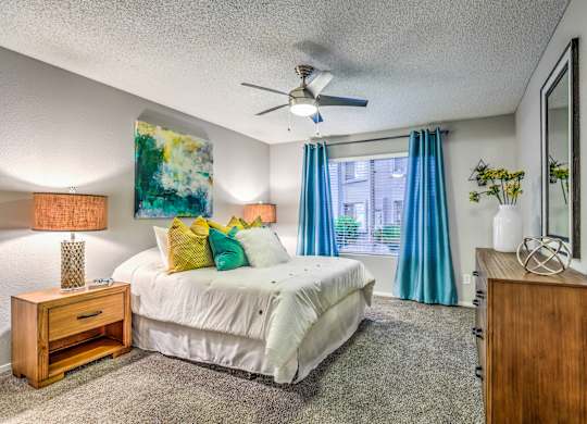 A bedroom with a bed, nightstand, and a painting on the wall.