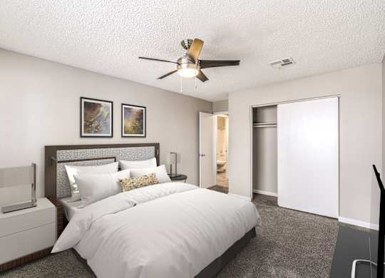 A bedroom with a large bed, a ceiling fan, and two pictures on the wall.