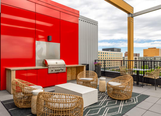 a rooftop patio with wicker chairs and a hot dog cart and a red wall