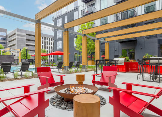 a patio with red chairs and tables and a fire pit