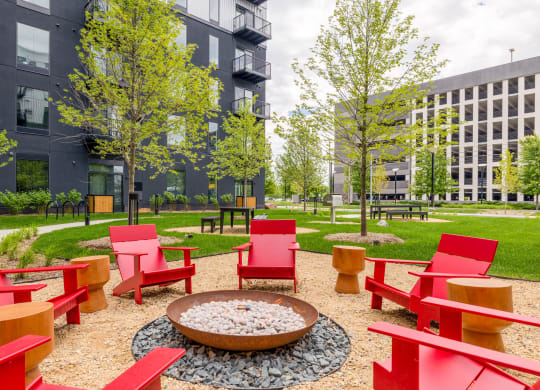 a courtyard with red chairs and a fire pit
