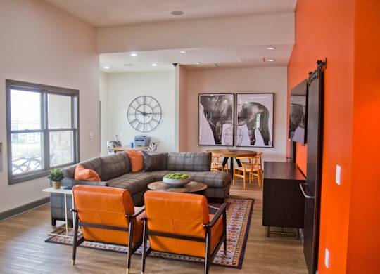 A living room with a grey couch and orange chairs.