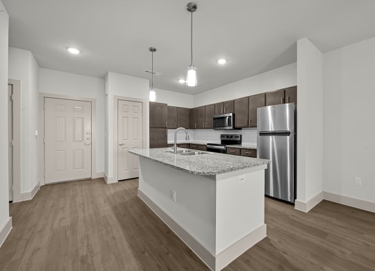 an empty kitchen with a marble counter top and a stainless steel refrigerator