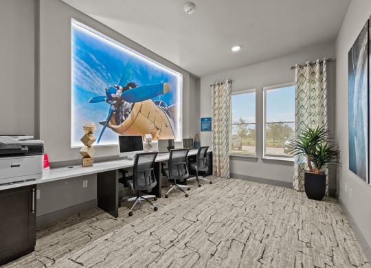 a conference room with desks and chairs and a large screen on the wall