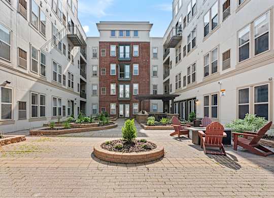 A courtyard with a brick circle in the middle and a red bench on the right.