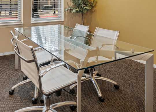 A conference room with a glass table and chairs.