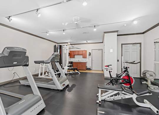 A gym with treadmills, a stationary bike, and a weight bench.