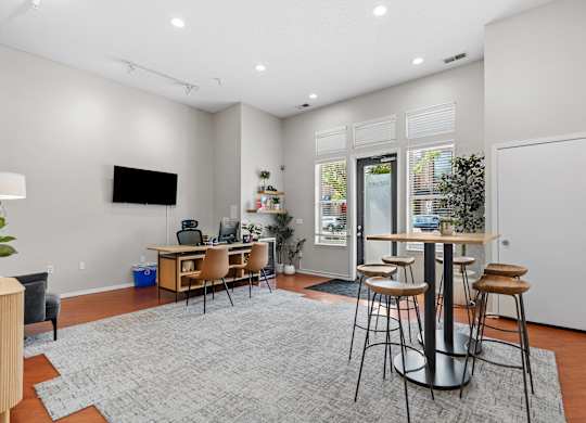 A modern living room with a grey rug and a television on the wall.