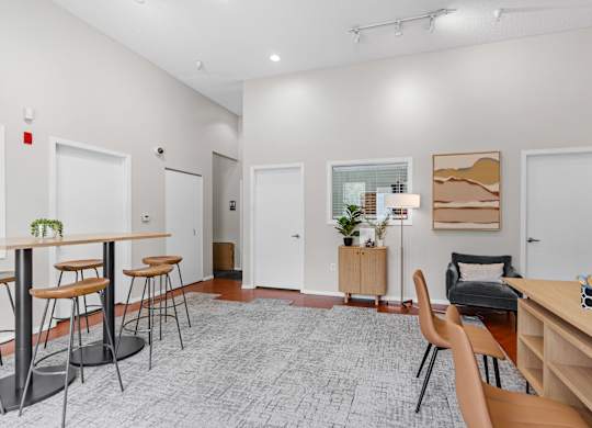 A room with a desk, chairs, and a potted plant.