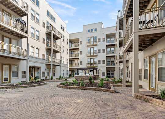 A courtyard surrounded by apartment buildings with a clear blue sky.