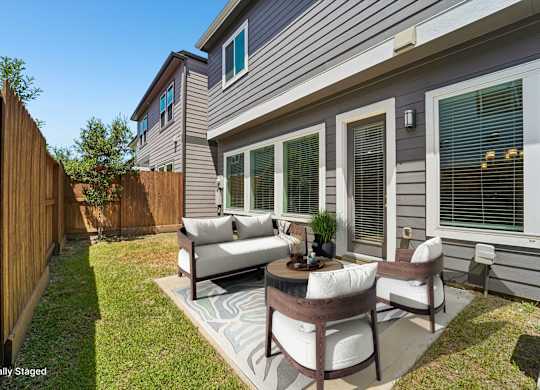 A patio with a table and chairs is in front of a house.