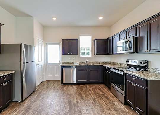 A kitchen with dark wood cabinets and stainless steel appliances.