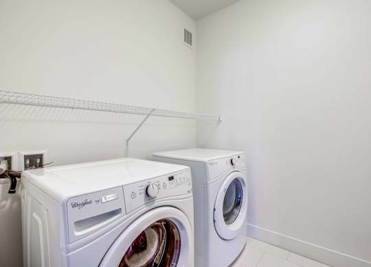 A white Whirlpool washing machine and dryer in a laundry room.