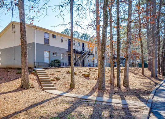 A tree-lined street with apartment buildings on either side.