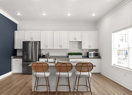 A kitchen with white cabinets and a stainless steel refrigerator.