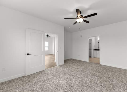 A spacious room with a ceiling fan and carpeted floor.