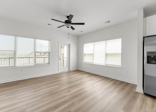 A spacious room with a ceiling fan and wooden flooring.