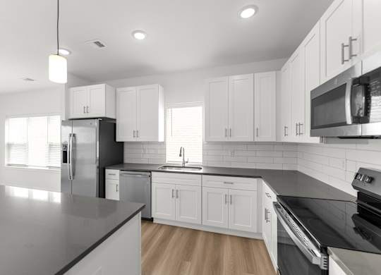 A modern kitchen with white cabinets and stainless steel appliances.