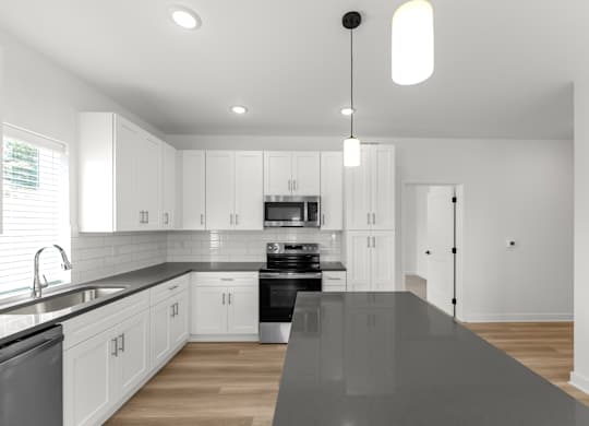 A modern kitchen with white cabinets and a black countertop.