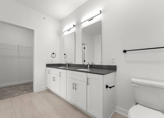 A white bathroom with a toilet, sink, and a mirror.