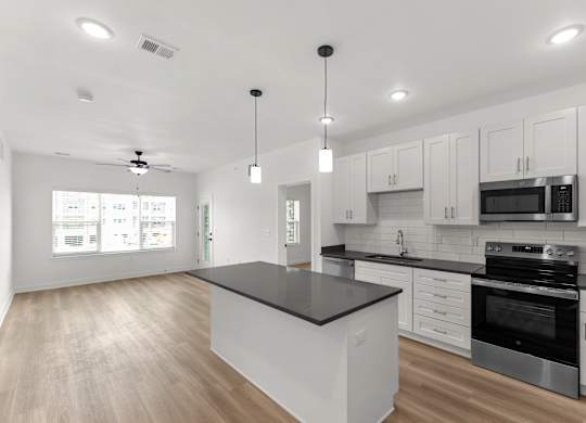 A modern kitchen with a black countertop and stainless steel appliances.