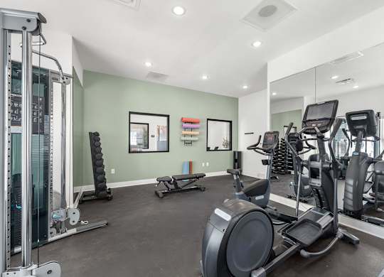 A gym with a variety of equipment including treadmills, weights, and exercise machines.