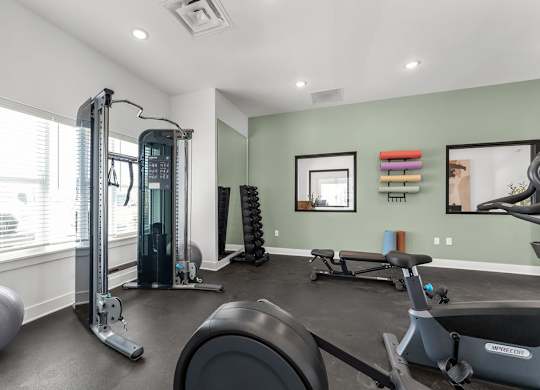 A home gym with a variety of equipment including a treadmill, weights, and a stationary bike.