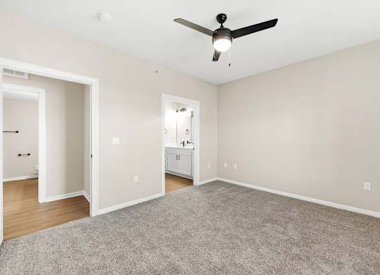 A room with a ceiling fan and carpeted floor.