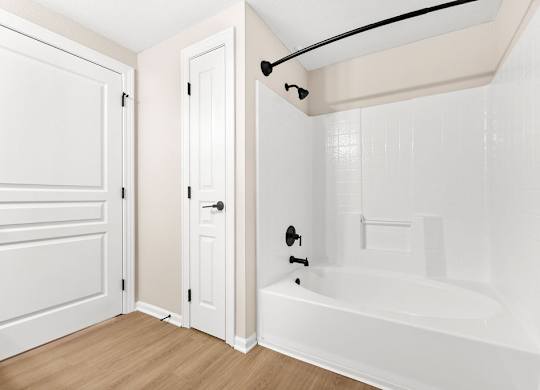 A white bathroom with a tub and a towel rack.