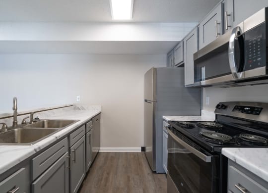 an empty kitchen with stainless steel appliances and white counter tops