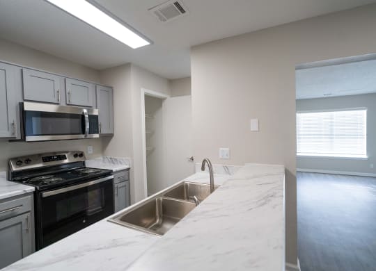 an empty kitchen with white marble counter tops and stainless steel appliances