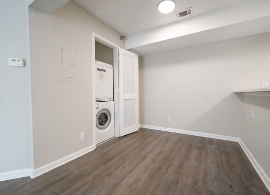an empty room with a washer and dryer in it and a white wall