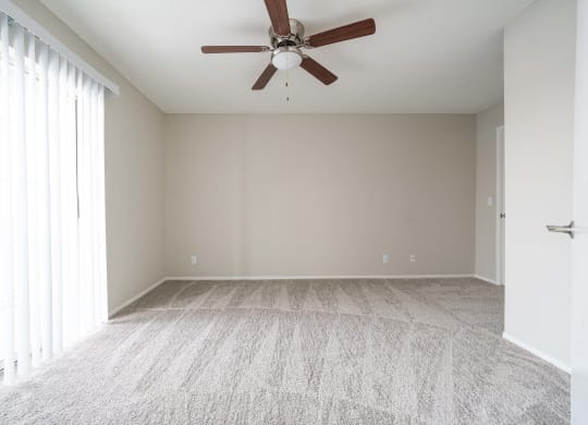an empty living room with a ceiling fan