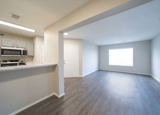 an empty living room and kitchen with hard wood flooring